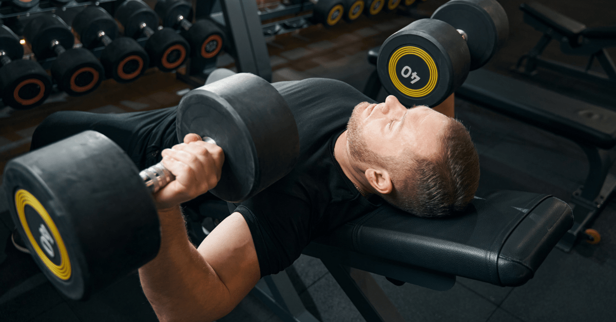 A person building their upper body with the dumbbell bench press exercise.